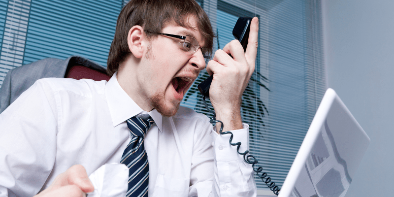 Angry business man yelling into a phone with clenched fists