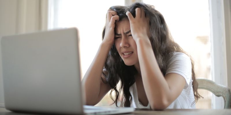 Woman at computer with head in hands